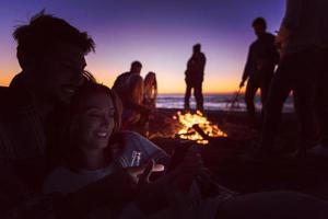 paar genieten van vreugdevuur met vrienden Aan strand foto