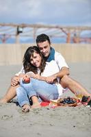 jong paar genieten van picknick Aan de strand foto