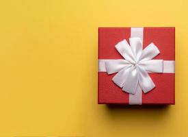 rood geschenk doos met wit boog Aan geel achtergrond,plat leggen foto