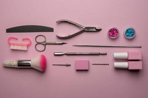 reeks van manicure gereedschap en accessoires Aan een roze achtergrond. hardware manicure, plat leggen. foto