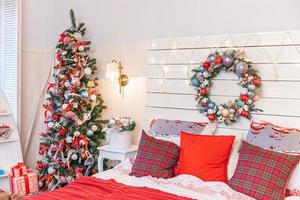 klassiek interieur kamer met Kerstmis boom en traditioneel wit rood decoraties. modern schoon wit klassiek stijl interieur ontwerp appartement slaapkamer. Kerstmis vooravond Bij huis. minimalistische huis ontwerp. foto