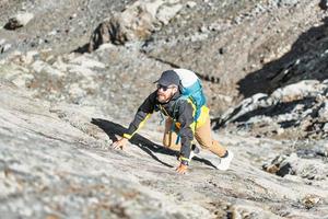 Mens klimt omhoog rots in berg foto