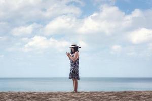 portret van Aziatische vrouw met behulp van mobiele telefoon tegen blauwe hemel foto