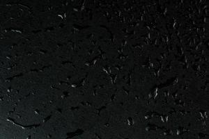 macro achtergrond van zwart vlak rubber oppervlakte met water druppels foto
