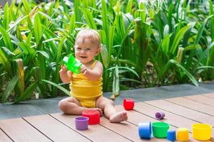 glimlachen weinig meisje spelen buitenshuis met kleurrijk plastic bouwer Aan een achtergrond van groen planten. foto