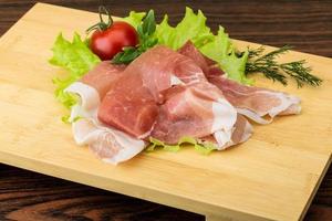 prosciutto Aan houten bord en houten achtergrond foto