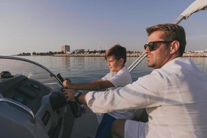 vader en zoon genieten hun vakantie samen terwijl rijden een luxe boot Bij zee. selectief focus foto