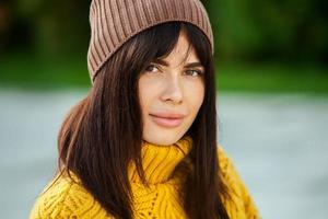 mooi Europese brunette gekleed in een geel wollen trui en hoed buiten. de mooi meisje wie draagt dik elegant herfst kleren in koel het weer. foto