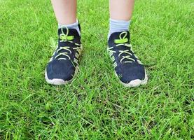 jongen staand Aan de gras gazon. voeten in sportschoenen. foto