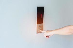 hand- vinger druk op de lift knop, vrouw aan het wachten voor lift in kantoor of appartement foto