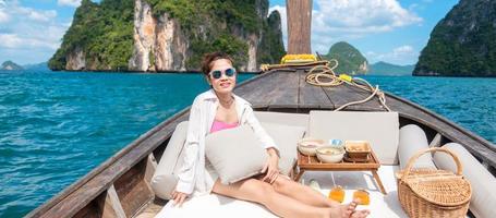 vrouw toerist in privé longtail boottocht naar eiland met exotisch eten picknick, krabi, thailand. oriëntatiepunt, bestemming, reizen naar Azië, vakantie, reislust en vakantieconcept foto