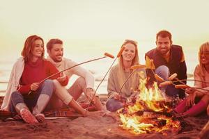 groep van jong vrienden zittend door de brand Bij strand foto