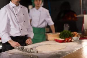 chef voorbereidingen treffen deeg voor pizza foto