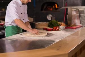 chef voorbereidingen treffen deeg voor pizza foto