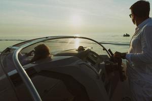 een senior paar in gewoontjes outfits met hun zoon genieten terwijl rijden een boot Bij zee Bij zonsondergang. de concept van een gelukkig familie. selectief focus foto