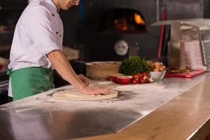 chef voorbereidingen treffen deeg voor pizza foto