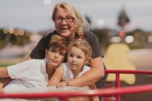 een ouder grootmoeder is spelen met haar kleinkinderen in een park Bij zonsondergang. selectief focus foto