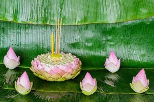 roze lotus bloemblad krathong siert met haar stuifmeel, kroon bloem, wierook stok en kaars voor Thailand vol maan of loy krathong festival Aan banaan bladeren achtergrond. foto