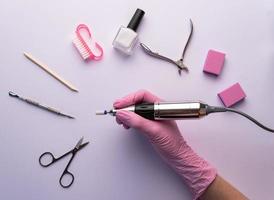 een manicure in handschoenen houdt een nagel oefening. foto