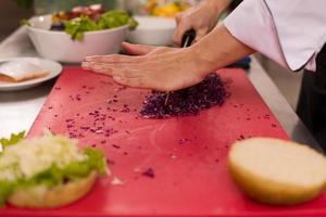 chef snijdend salade voor hamburger foto