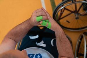een gehandicapt basketbal speler zet Aan een korset en verbanden Aan zijn armen en vingers in voorbereiding voor een spel in de arena foto
