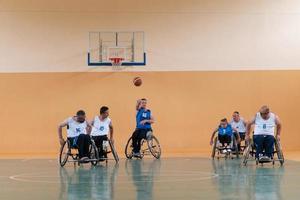 gehandicapten oorlog veteranen in rolstoelen met professioneel uitrusting Speel basketbal bij elkaar passen in de zaal.de concept van sport- met handicaps foto