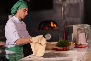 chef voorbereidingen treffen deeg voor pizza foto