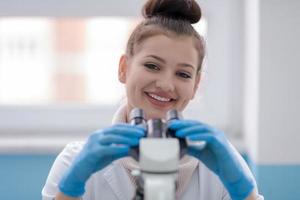 vrouw leerling wetenschapper op zoek door een microscoop foto