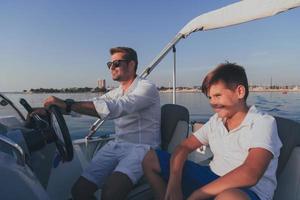 vader en zoon genieten hun vakantie samen terwijl rijden een luxe boot Bij zee. selectief focus foto