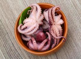 gemarineerde octopus in een kom op houten achtergrond foto