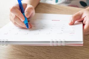 vrouw hand- met pen schrijven Aan kalender datum bedrijf planning afspraak vergadering concept foto