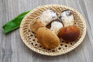 wilde paddestoelen in een mand op houten achtergrond foto