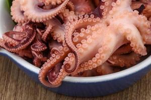 gemarineerde octopus in een kom op houten achtergrond foto