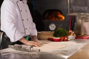 chef voorbereidingen treffen deeg voor pizza foto