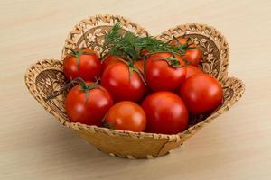 kers tomaten in een mand Aan houten achtergrond foto