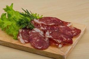 gesneden salami Aan houten bord en houten achtergrond foto