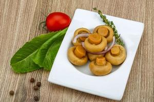 ingelegde champignon in een kom op houten achtergrond foto