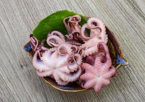 gemarineerde octopus in een kom op houten achtergrond foto