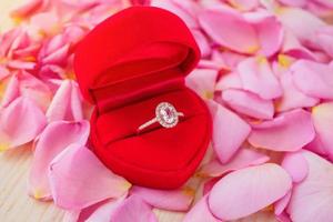 elegante bruiloft diamanten ring in rood hart juwelendoos op mooie roze roze bloemblaadje achtergrond close-up foto