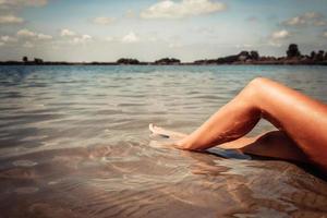 onherkenbaar vrouw ontspannende Aan zanderig strand. foto