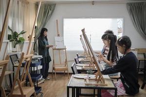 een vrouw Aziatisch leraar geeft les en demonstreert naar de kinderen Aan acryl kleur afbeelding schilderij Aan canvas in kunst klas, creatief aan het leren met vaardigheid Bij de elementair school- studio onderwijs. foto