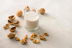 biologisch okkernoot noten en glas van okkernoot melk Aan steen achtergrond. foto