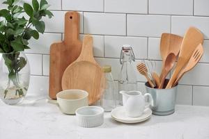 gemakkelijk rustiek keukengerei tegen wit houten muur ruw keramisch pot met houten Koken werktuig set, stapels van keramisch kommen, kruik en houten dienbladen. foto