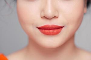 dichtbij omhoog visie van mooi vrouw lippen met koraal mat lippenstift foto