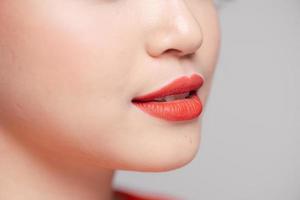 dichtbij omhoog visie van mooi vrouw lippen met koraal mat lippenstift foto
