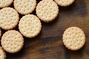 een ronde belegd broodje koekje met kokosnoot vulling leugens in groot hoeveelheden Aan een bruin houten oppervlak. foto van eetbaar behandelt Aan een houten achtergrond met kopiëren ruimte