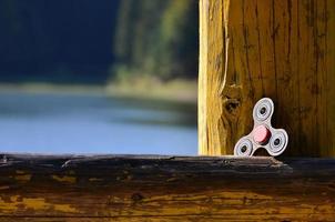 een houten spinner leugens Aan een houten bar tegen een achtergrond van rivier- water foto