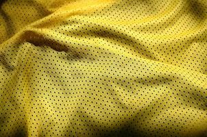 geel sport kleding kleding stof structuur achtergrond. top visie van geel kleding textiel oppervlak. helder basketbal shirt. tekst ruimte foto