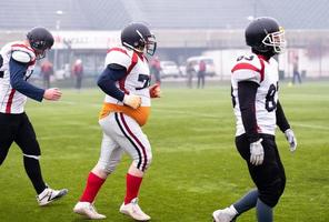 zelfverzekerd Amerikaans Amerikaans voetbal spelers weggaan de veld- foto