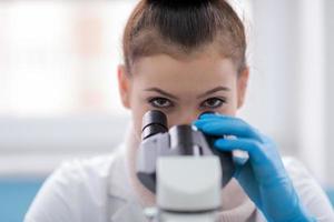 vrouw leerling wetenschapper op zoek door een microscoop foto